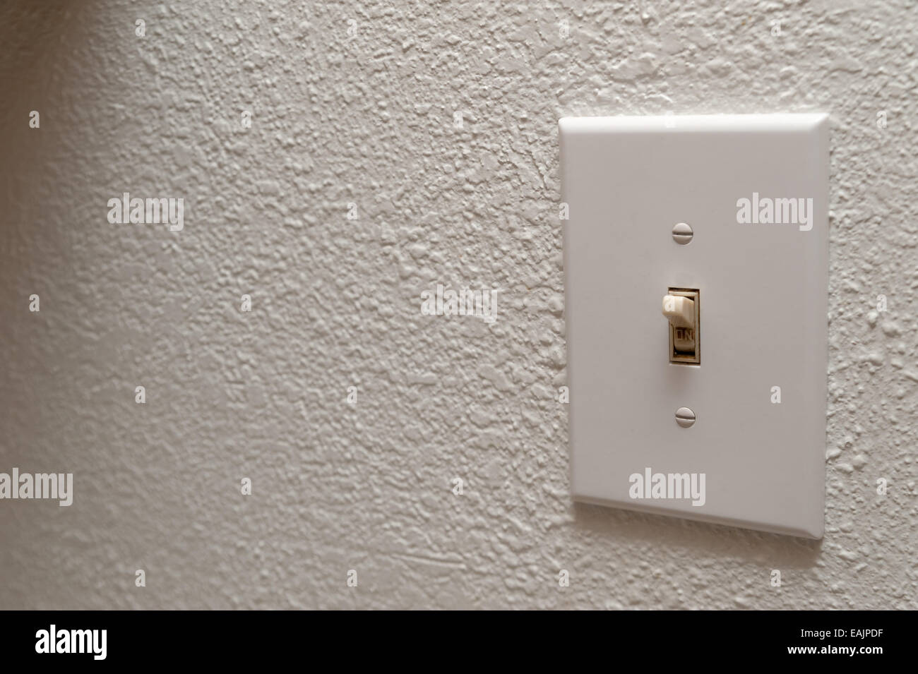 Hand turning wall light switch off Stock Photo