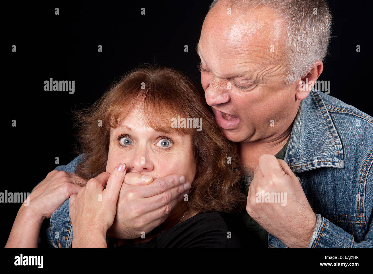 Man grabbing a woman from behind and threatening her with his fist. Stock Photo