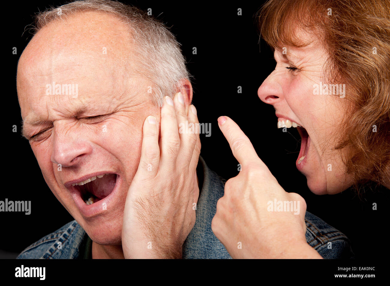 Middle aged couple having an argument, with the woman shouting and pointing finger at the crying man. Stock Photo