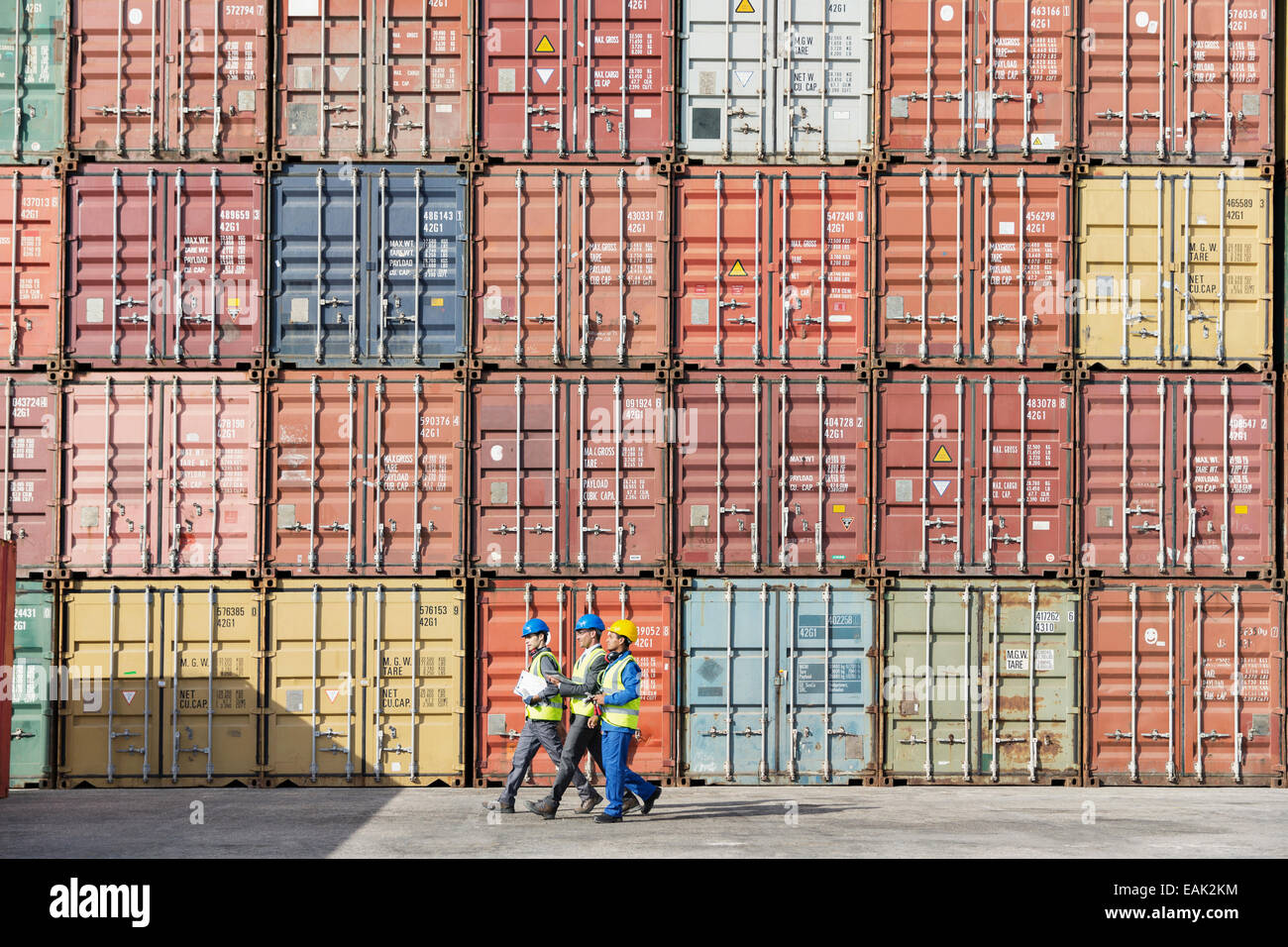 Workers walking together near stack of cargo containers Stock Photo