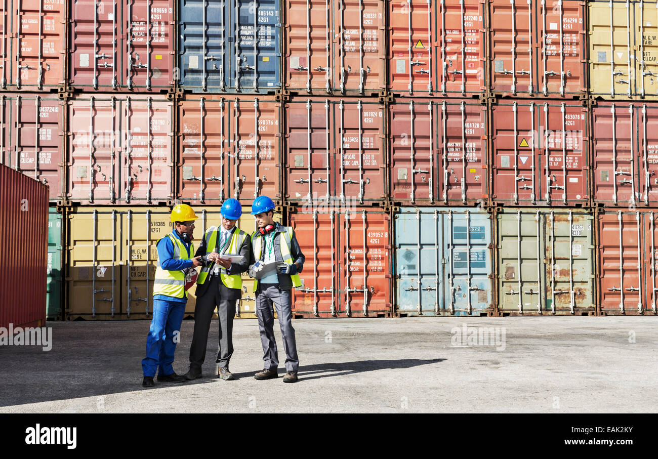 Worker and businessmen talking near cargo containers Stock Photo