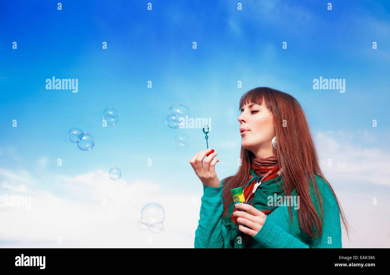 Beautiful brunette blowing bubbles against the sky Stock Photo