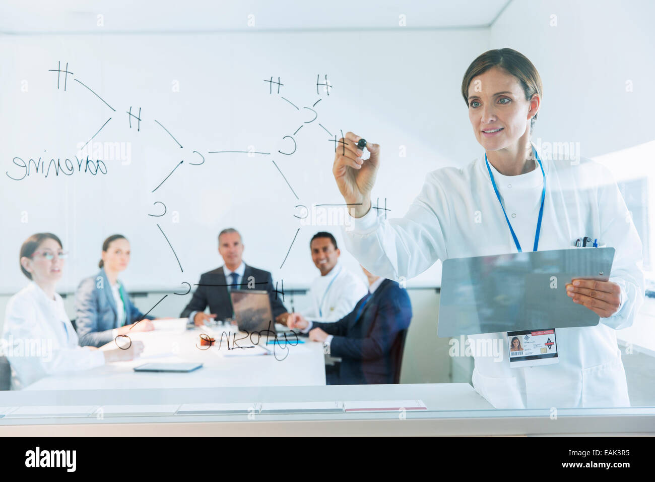 Scientist drawing chemical formula on glass for business people and colleagues Stock Photo