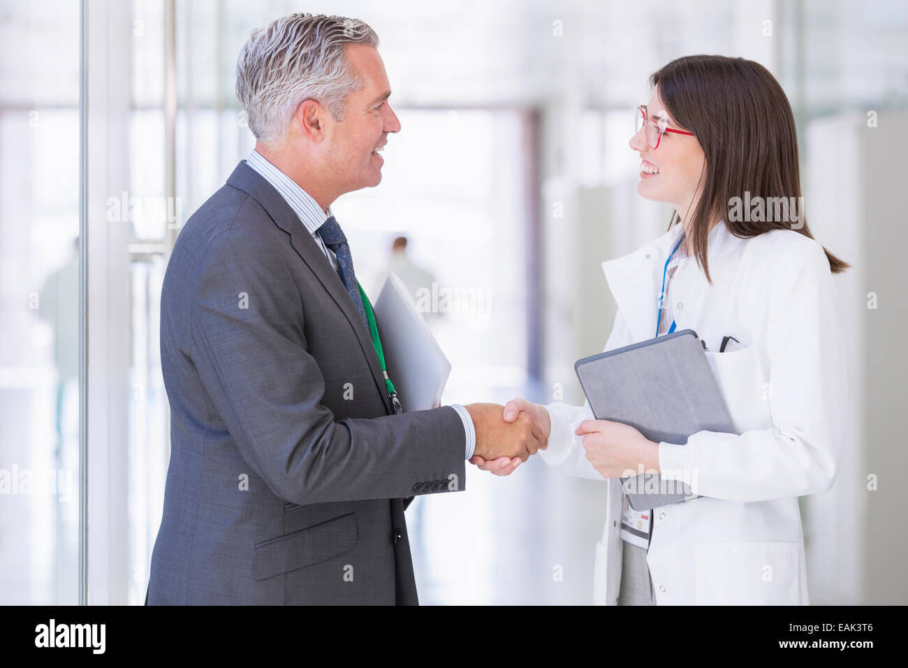 Scientist and businessman shaking hands in hallway Stock Photo