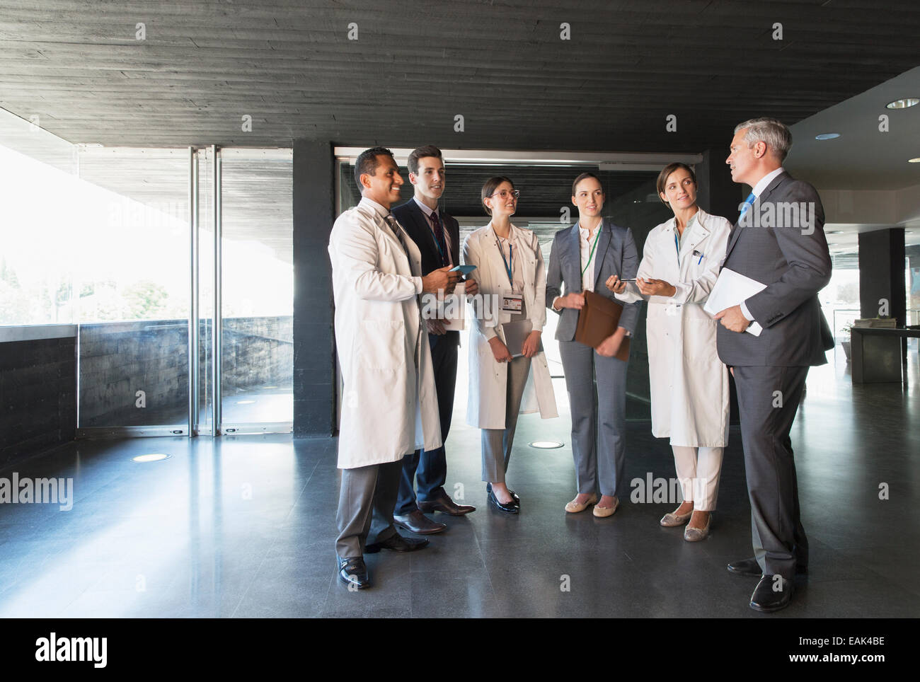 Scientists and business people talking in lobby Stock Photo