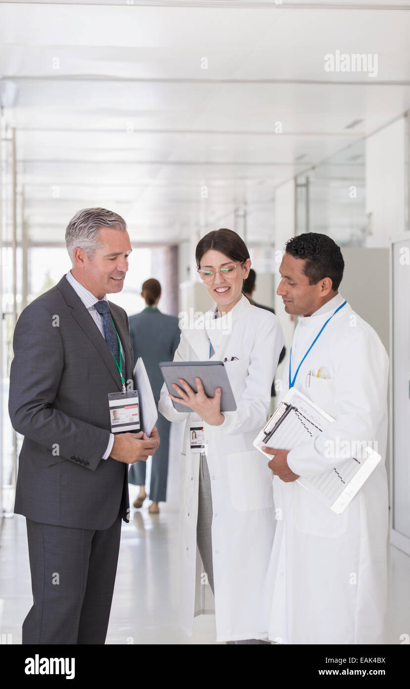 Scientists and businessman using digital tablet in hallway Stock Photo