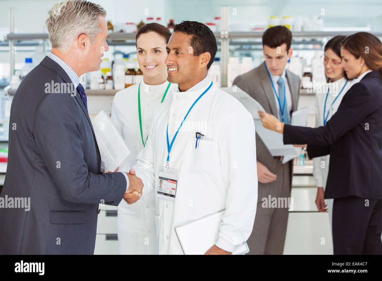Scientist and businessman shaking hands in laboratory Stock Photo