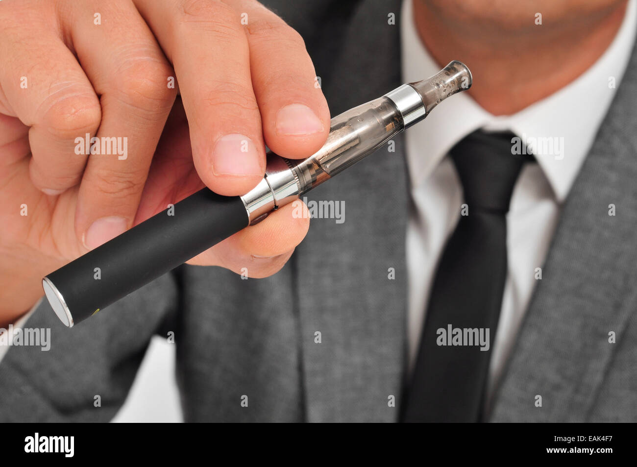 man wearing a suit vaping with an electronic cigarette Stock Photo