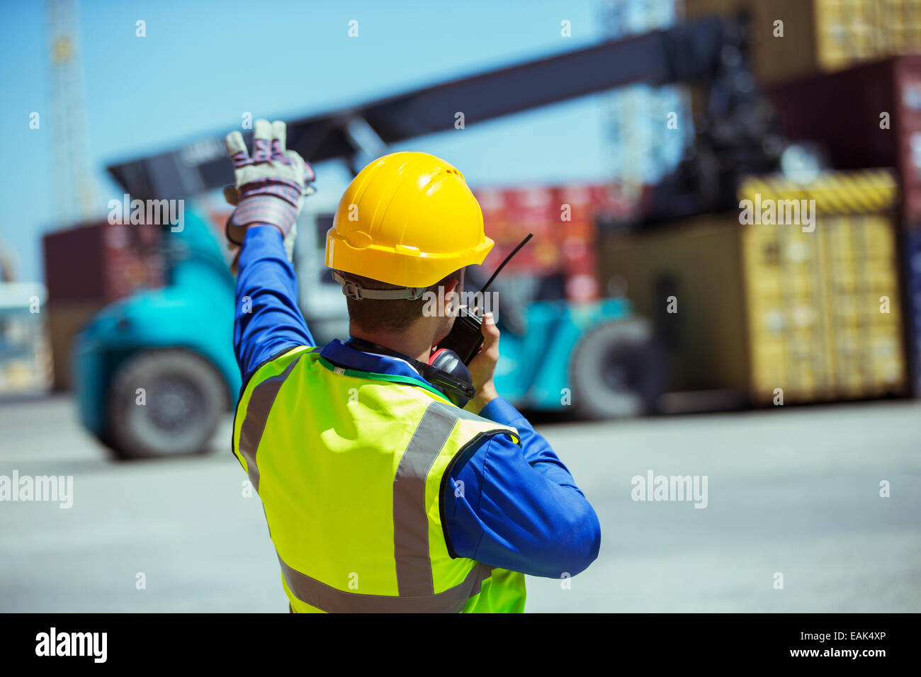 Worker using walkie-talkie near cargo containers Stock Photo