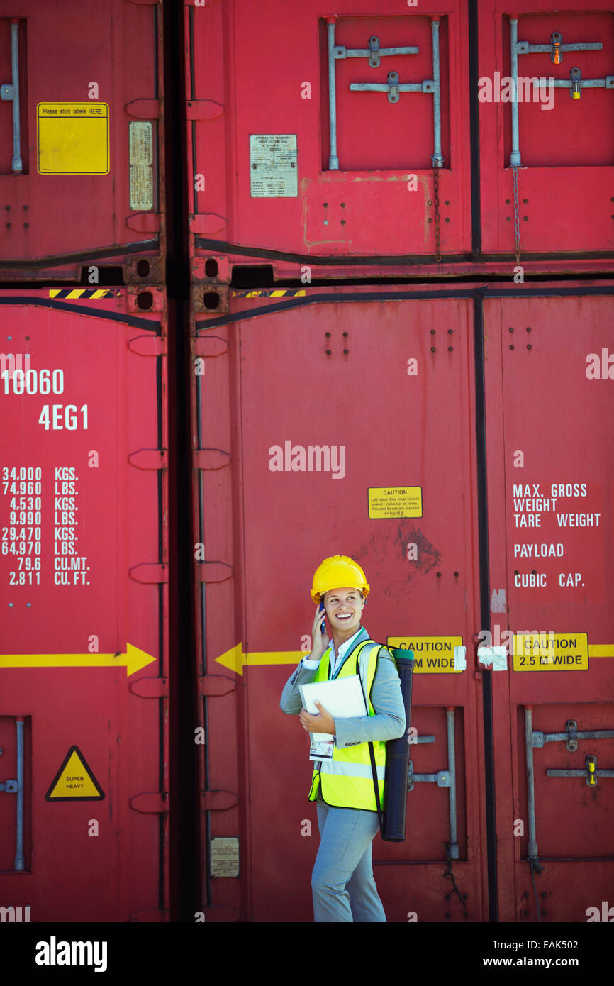 Businesswoman talking on cell phone near cargo containers Stock Photo