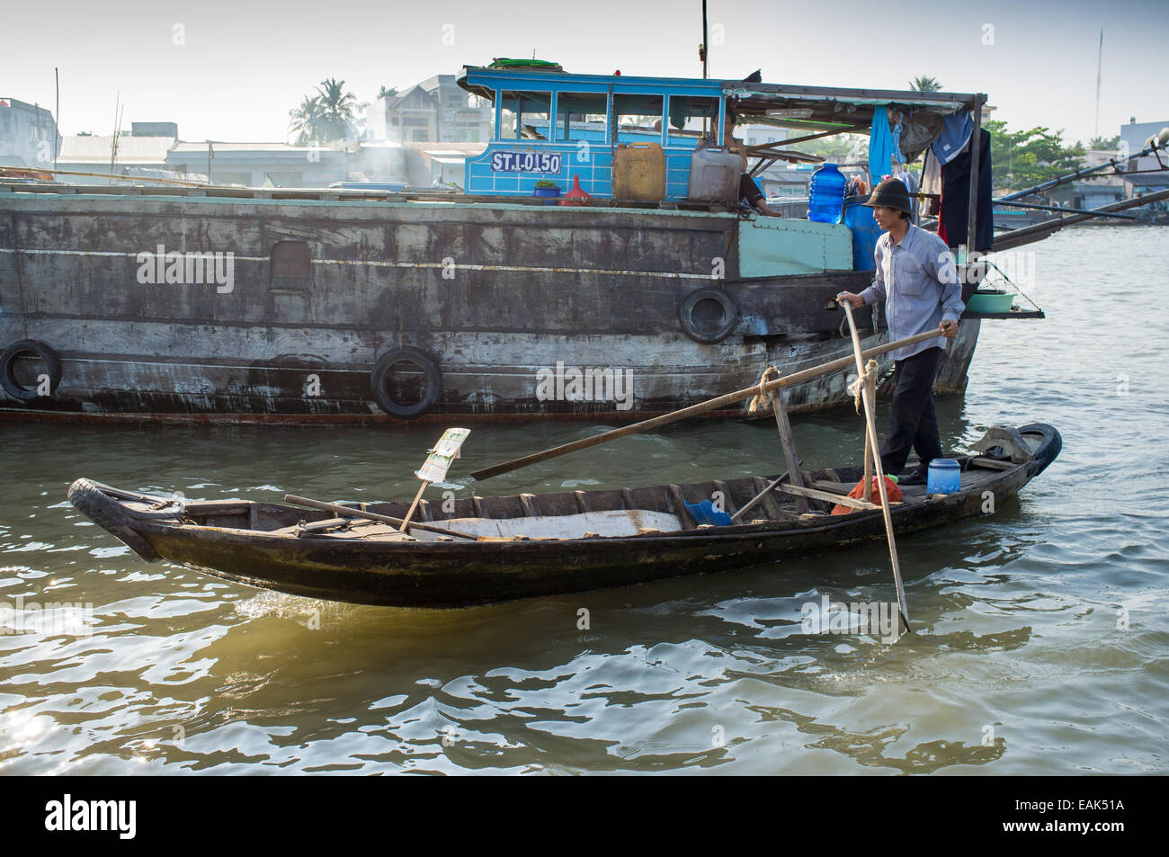 A man rowing her boat through the floating markets in the Mekong Delta ...