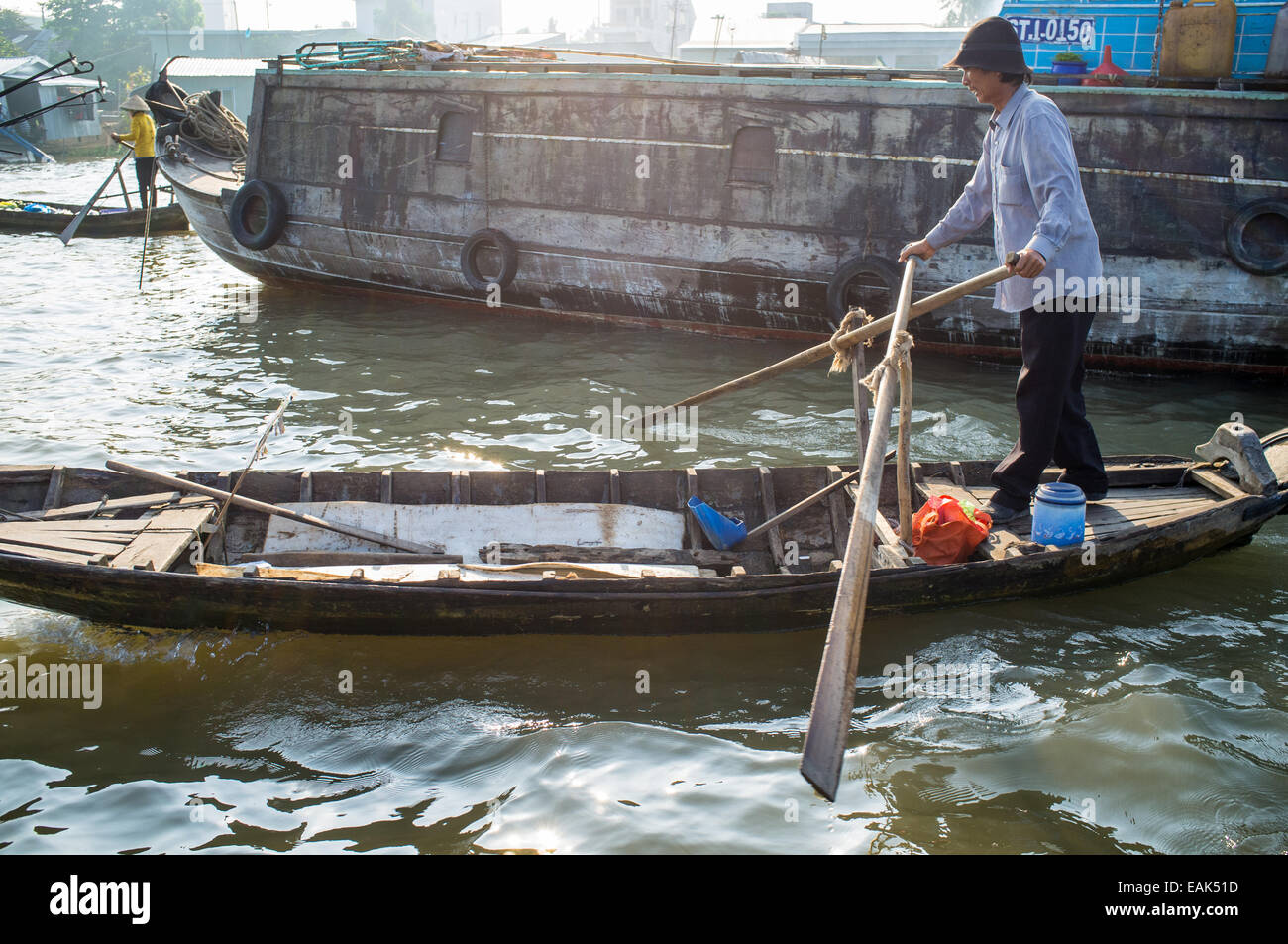 A man rowing her boat through the floating markets in the Mekong Delta ...