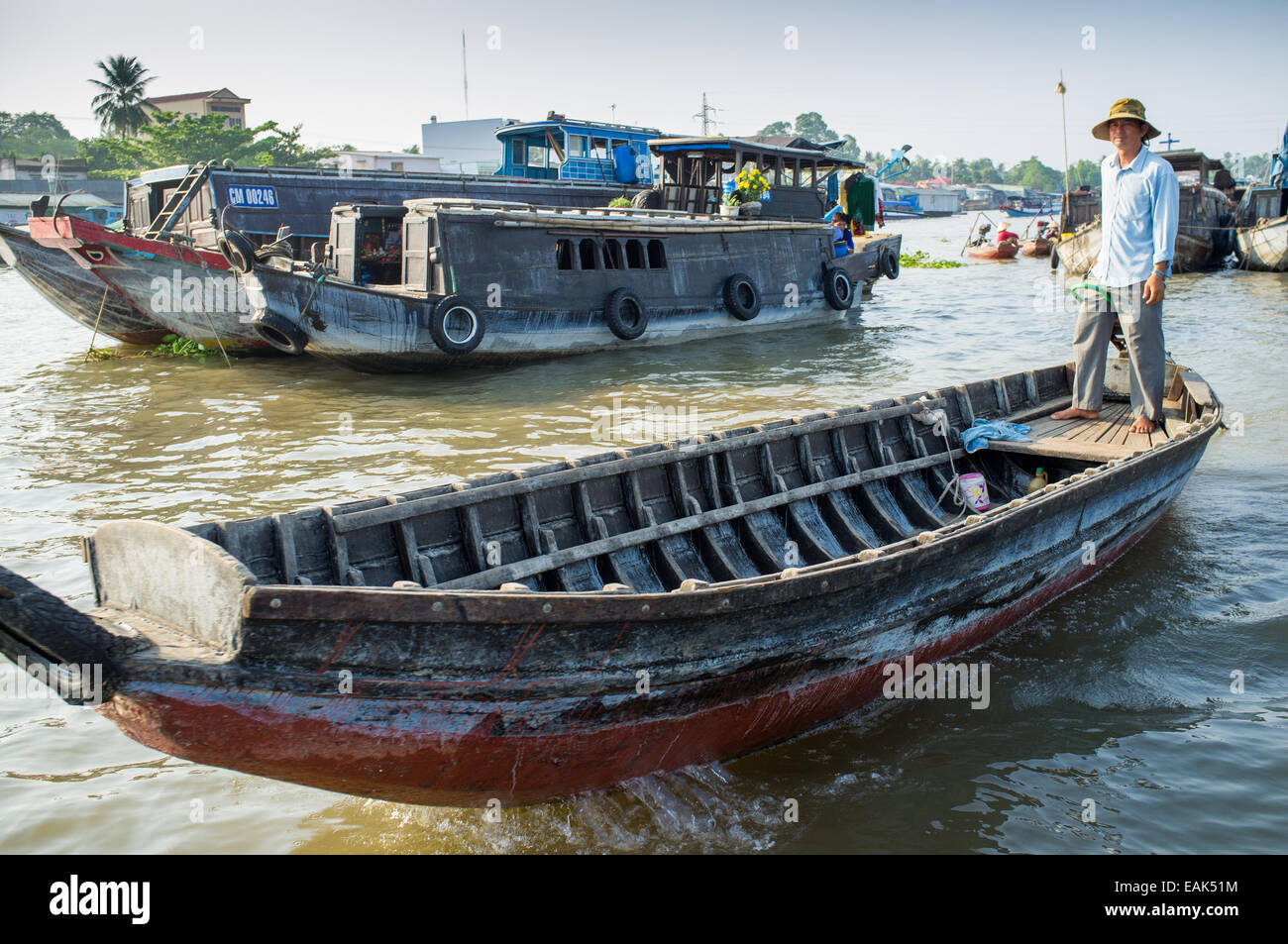 A man rowing her boat through the floating markets in the Mekong Delta ...