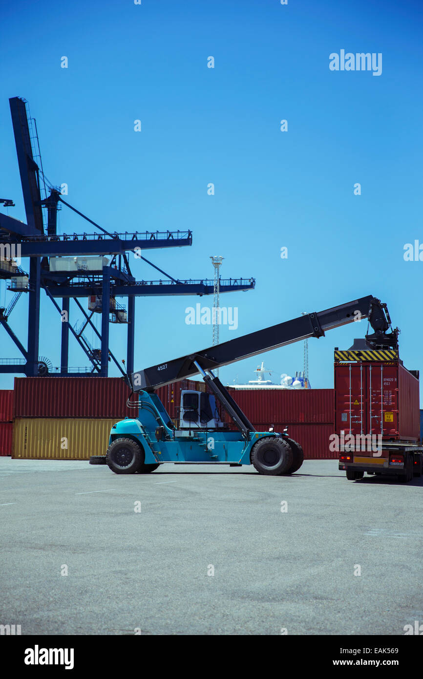 Crane lifting cargo container onto truck Stock Photo