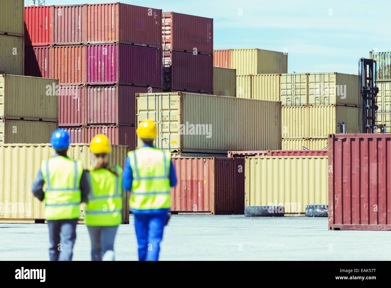 Workers and businessman walking near cargo containers Stock Photo