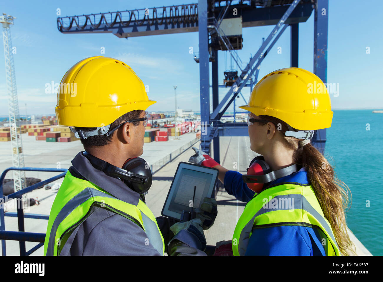 Workers using digital tablet on cargo crane Stock Photo