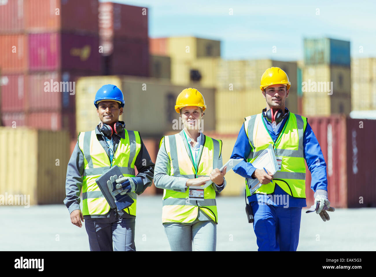 Businesswoman and workers walking near cargo containers Stock Photo