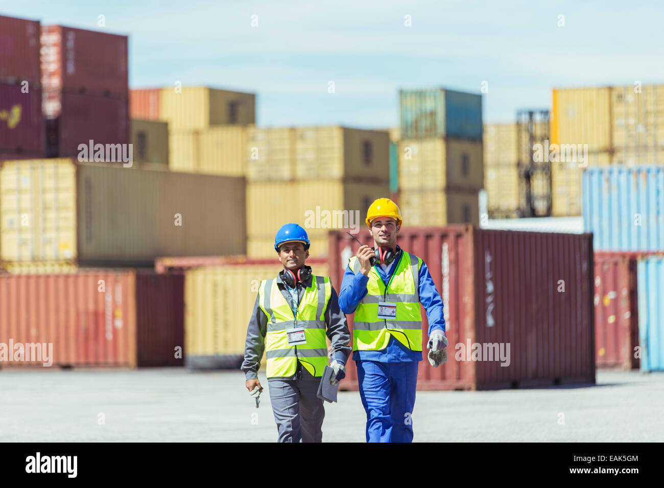 Worker and businessman walking near cargo containers Stock Photo