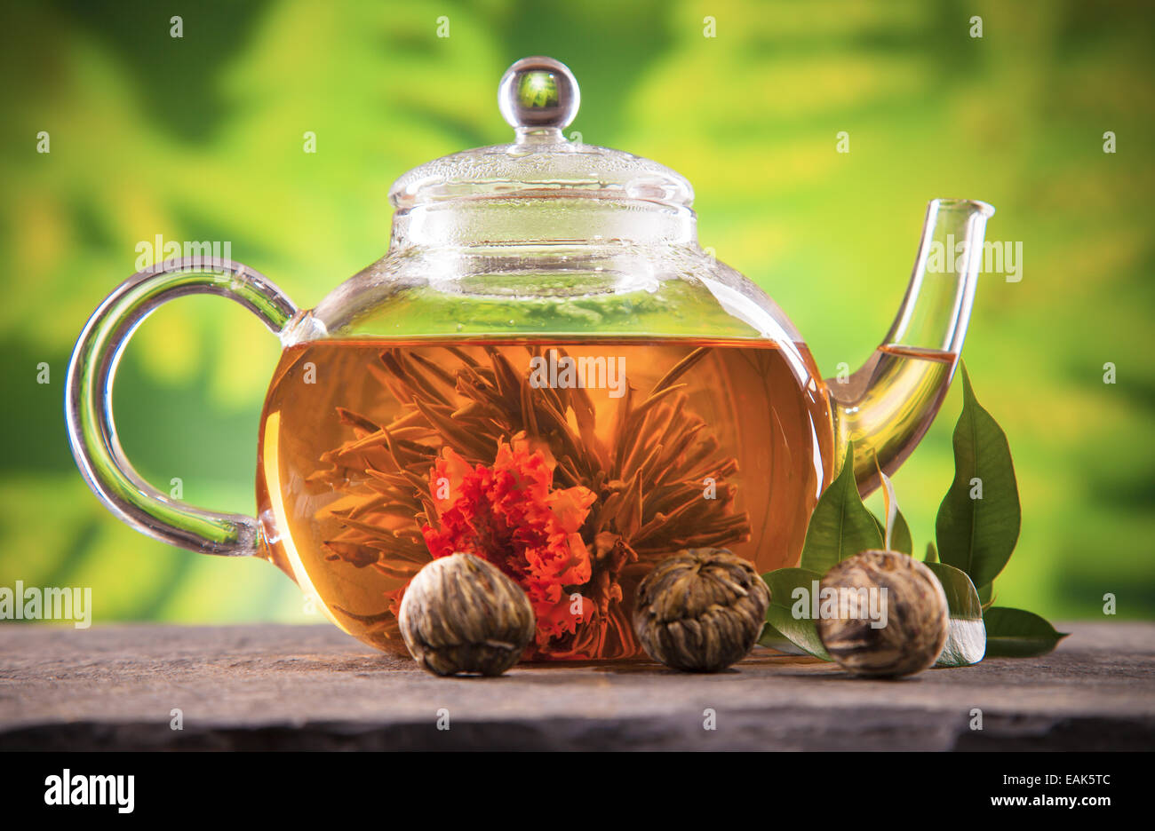 Teapot with blooming tea on blur green background Stock Photo Alamy