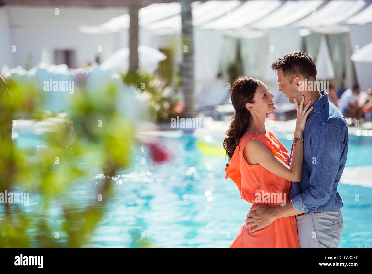Couple standing face to face by swimming pool Stock Photo