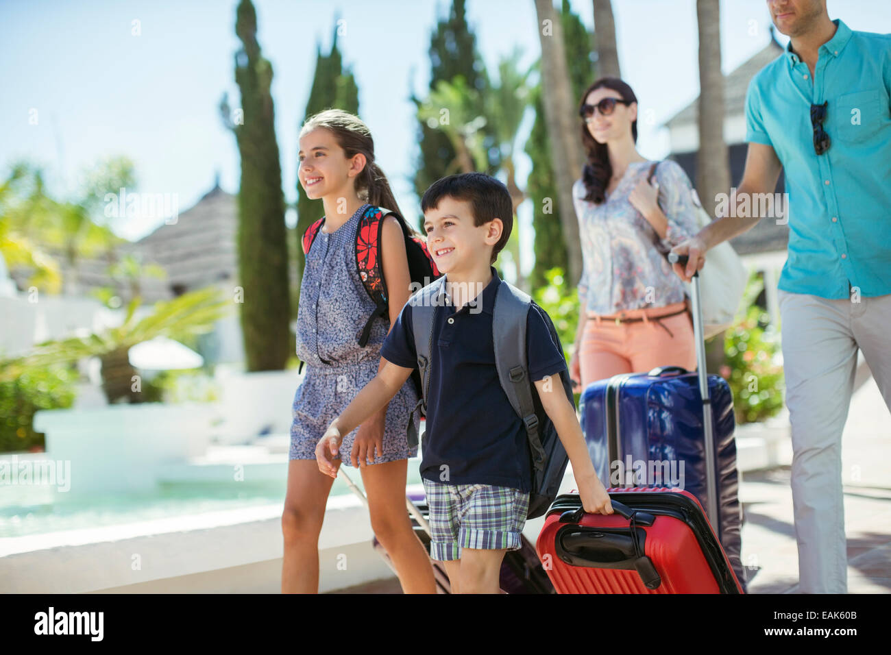 Family with suitcases walking towards tourist resort Stock Photo