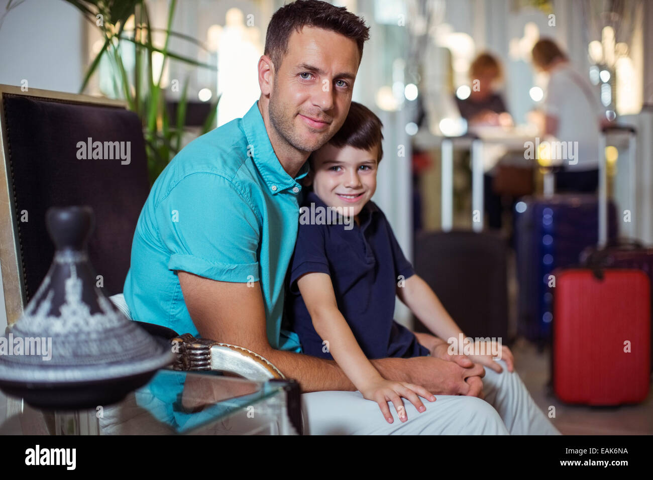 Portrait of man with son sitting in hotel lobby Stock Photo