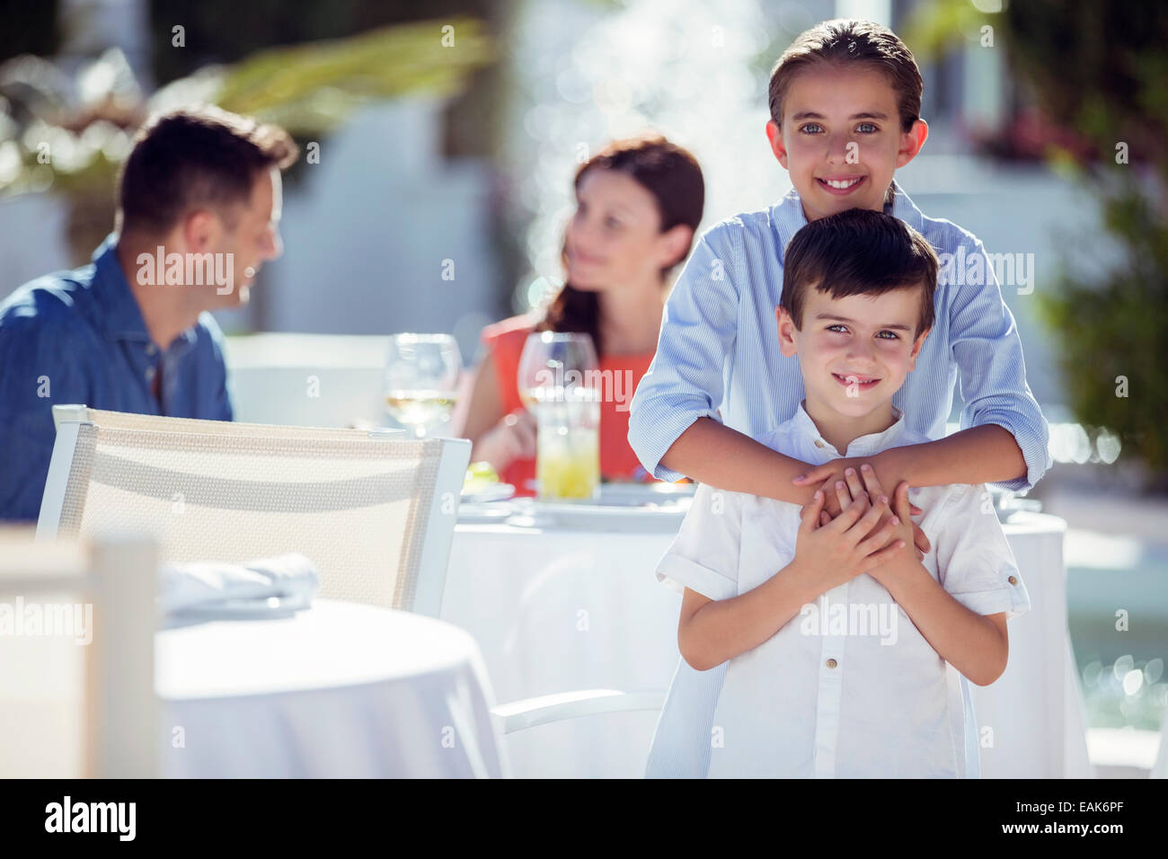 Portrait of smiling brother and sister, parents sitting at table in background Stock Photo