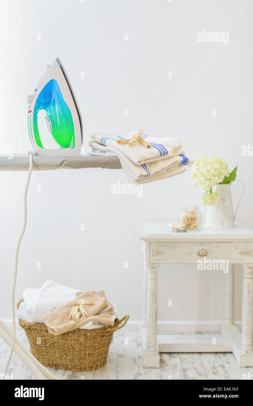 Utility room in the home with iron and basket of freshly laundered washing Stock Photo