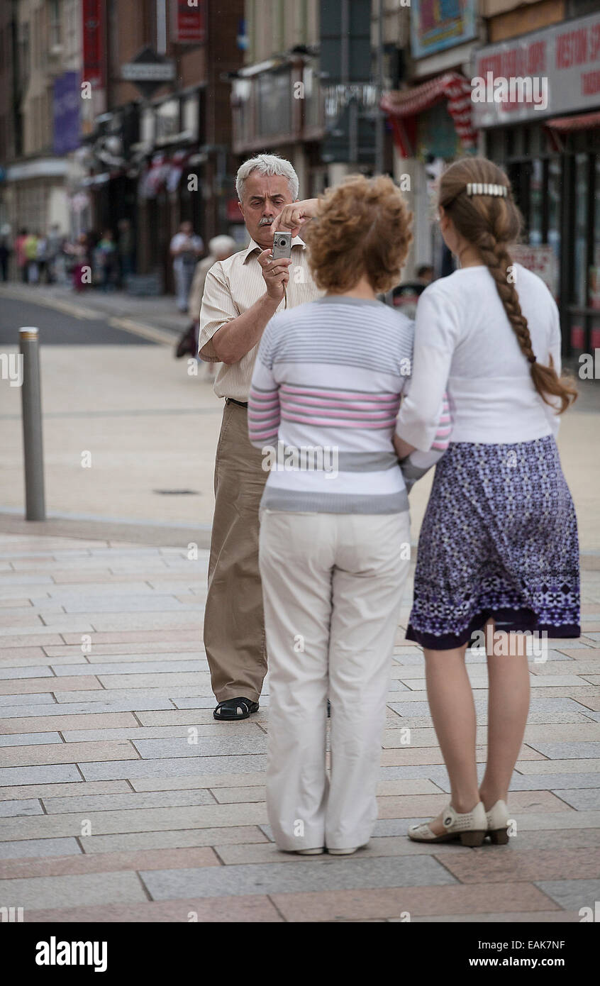 A mixed race European male age 50 plus taking a photograph of his wife and daughter. The photograph is shot on location and is i Stock Photo