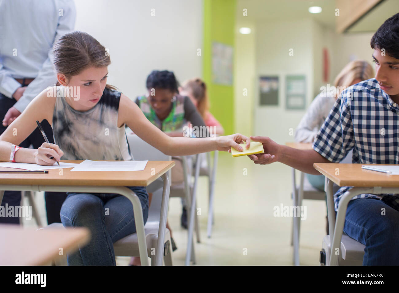 Students passing note between desks during GCSE examination Stock Photo