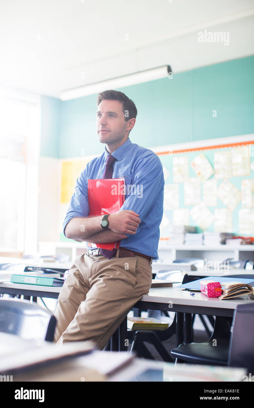Portrait of male teacher leaning at desk in classroom Stock Photo