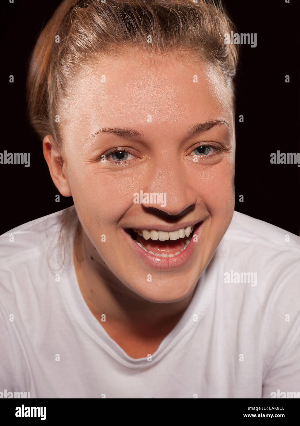 A color photograph of a white European female age 20-25 shot in casual clothes in a studio against a black background Stock Photo