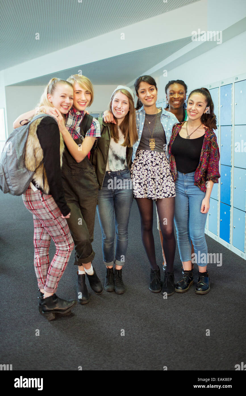 Group portrait of cheerful female students standing in locker room Stock Photo