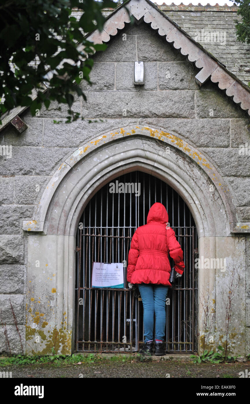 A child peers into a disused mortuary chapel in St Gluvias cemetery, Penryn, Cornwall Stock Photo