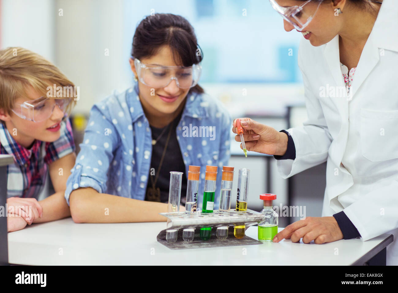 Teacher and students during chemistry lesson, wearing protective eyewear and looking at test tubes Stock Photo