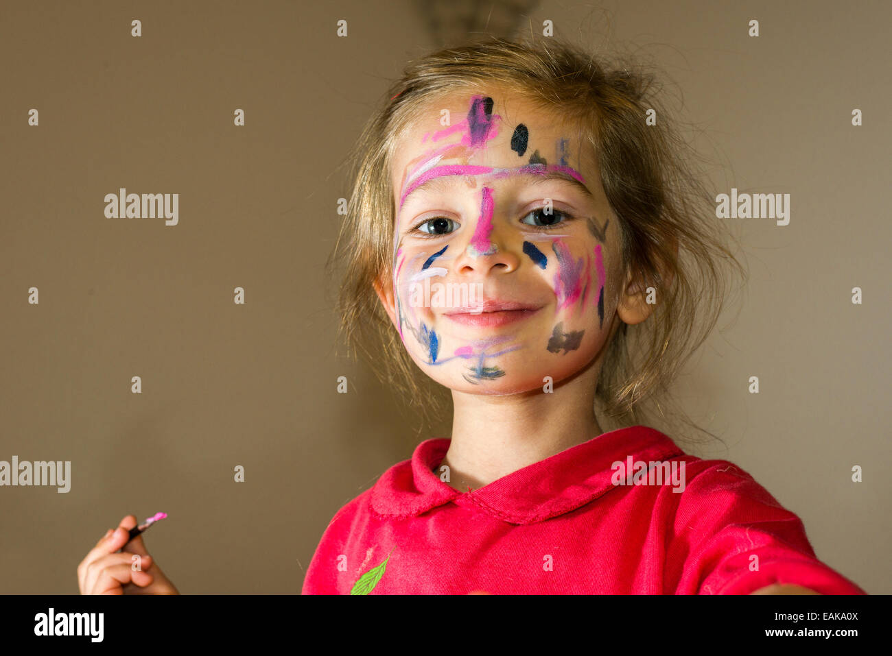 Girl painting her face with colourful watercolour, Germany Stock Photo