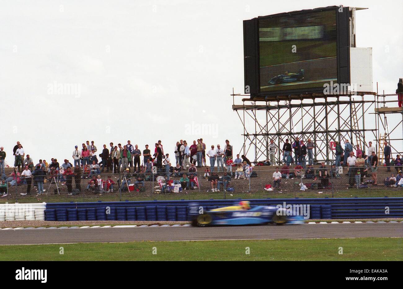 Three Flashes Racing F3 race car flashes past spectators and its own image on a giant TV, at ...