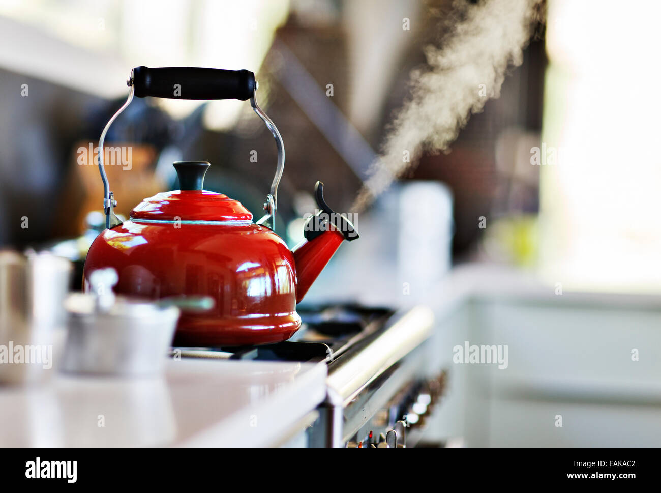 Red old fashion kettle on cooker with steam coming out Stock Photo