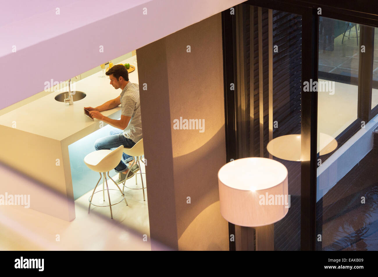 Elevated view of man using tablet pc in kitchen at night Stock Photo