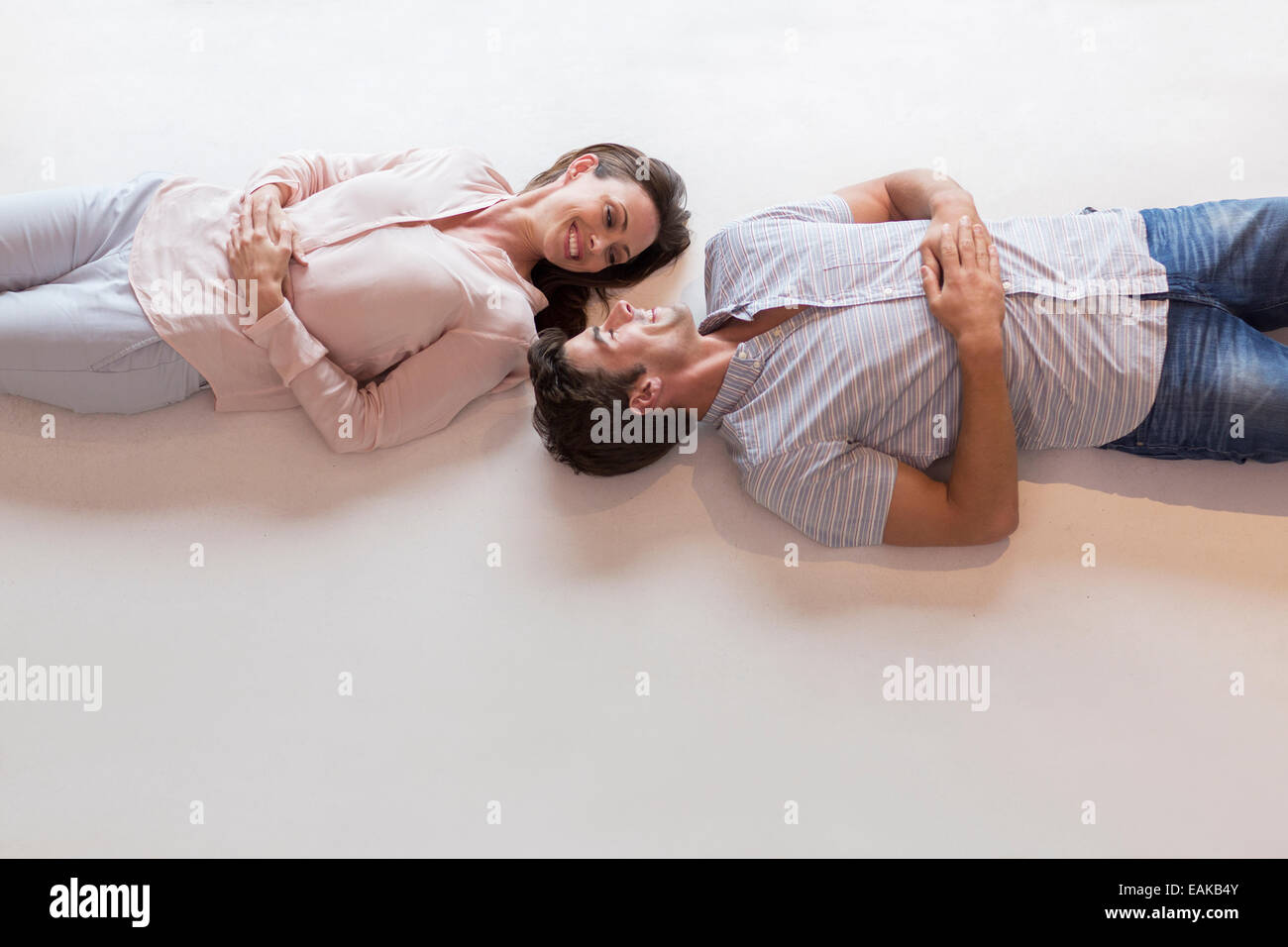 Couple looking at each other while lying on table Stock Photo