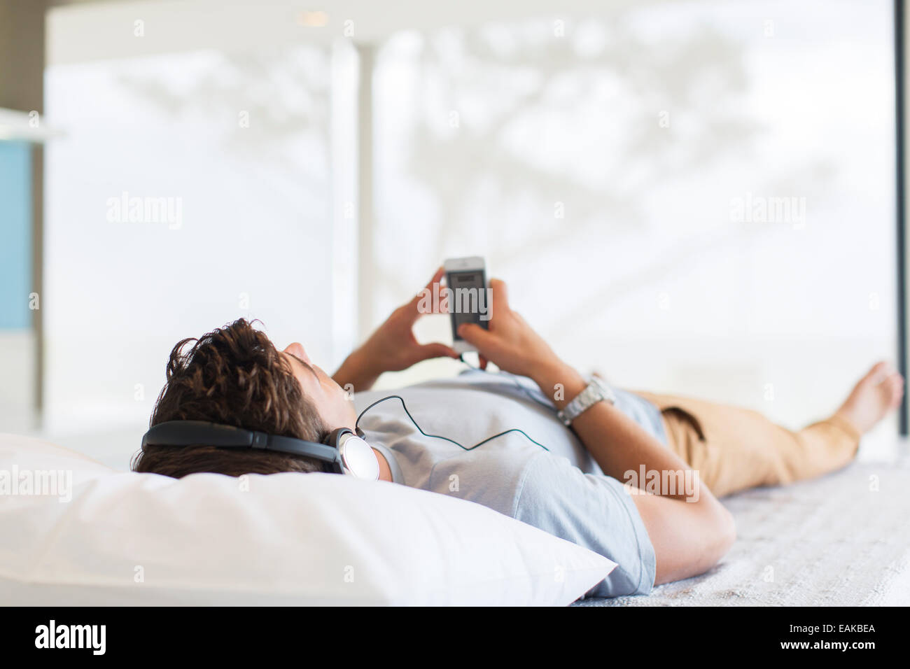 Man listening to music while lying on bed Stock Photo