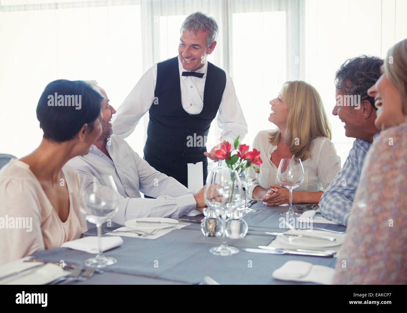 People sitting at restaurant table and talking to waiter Stock Photo