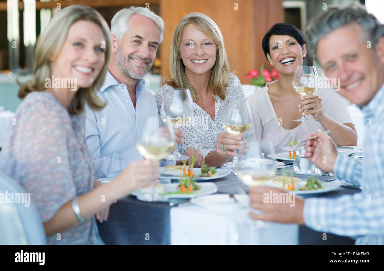 Portrait of smiling people toasting with white wine in restaurant Stock Photo