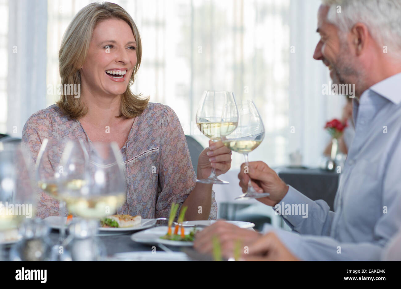 Smiling mature woman and man toasting with white wine at restaurant table Stock Photo