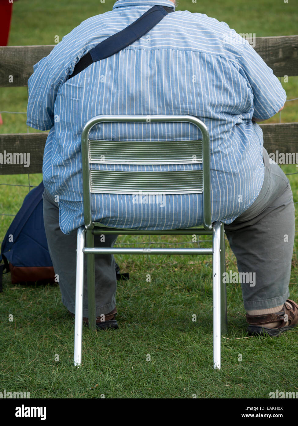 obese man sat on a small chair Stock Photo