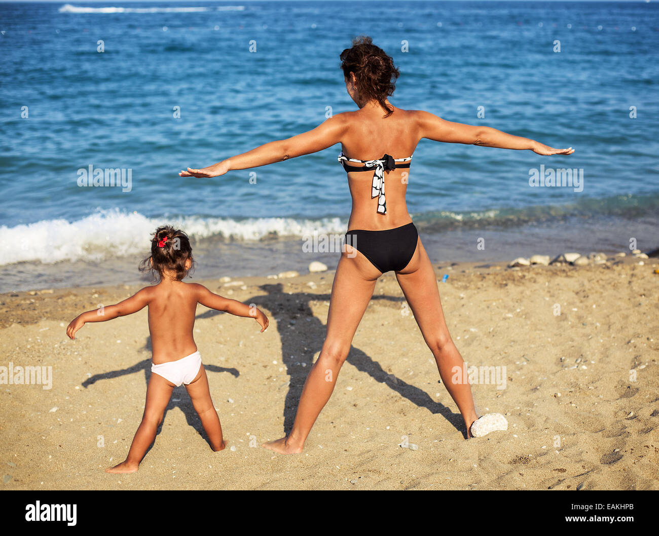 Mother and daughter doing exercise at the seaside. Stock Photo