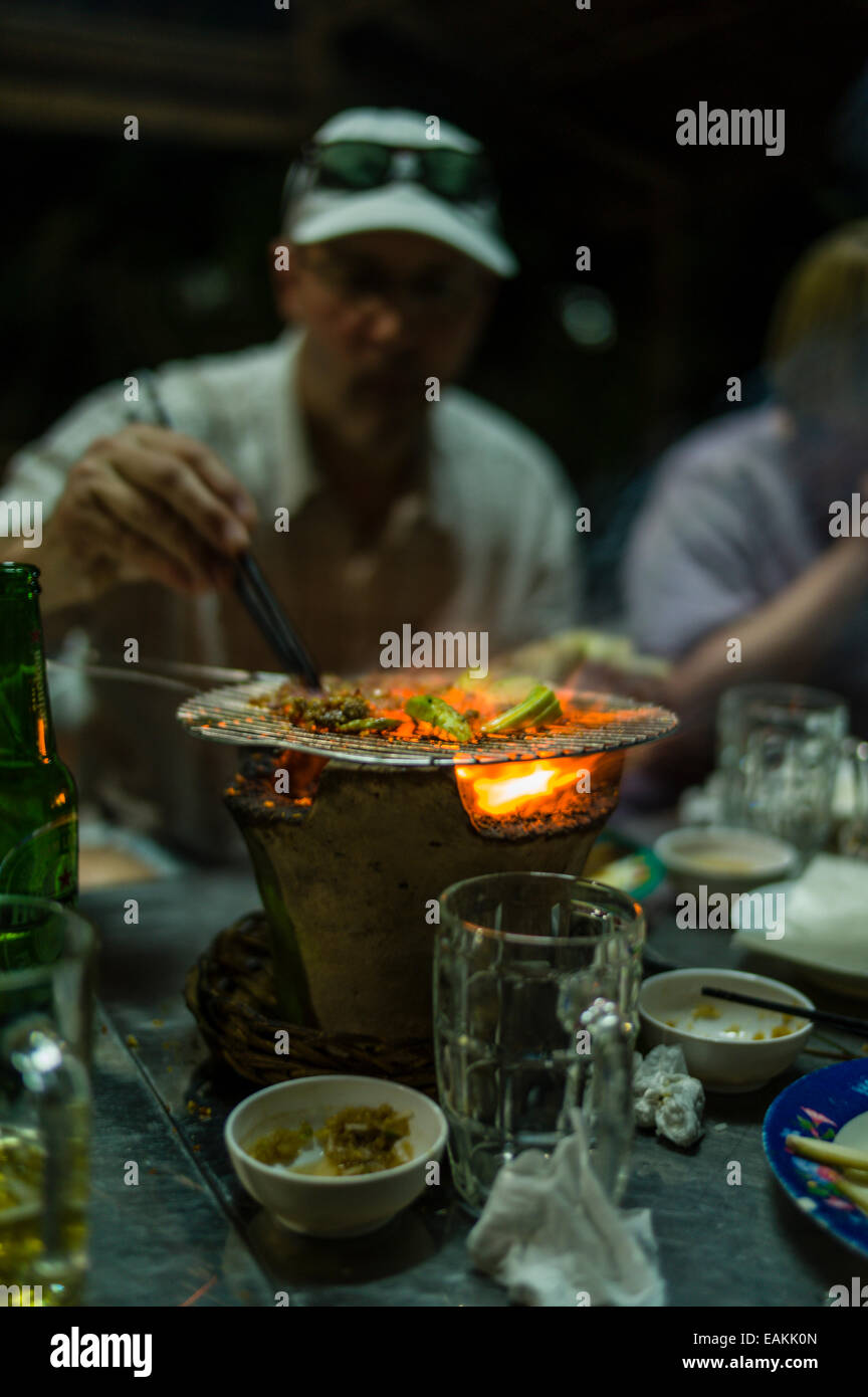 Beef and okra cooking on a tabletop charcoal grill in an outdoor
