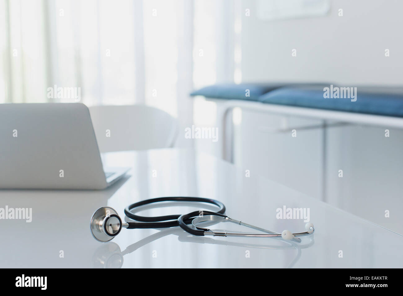 Stethoscope and laptop on white desk in doctors office Stock Photo