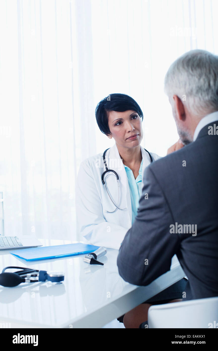 Female doctor and man sitting at desk in office Stock Photo