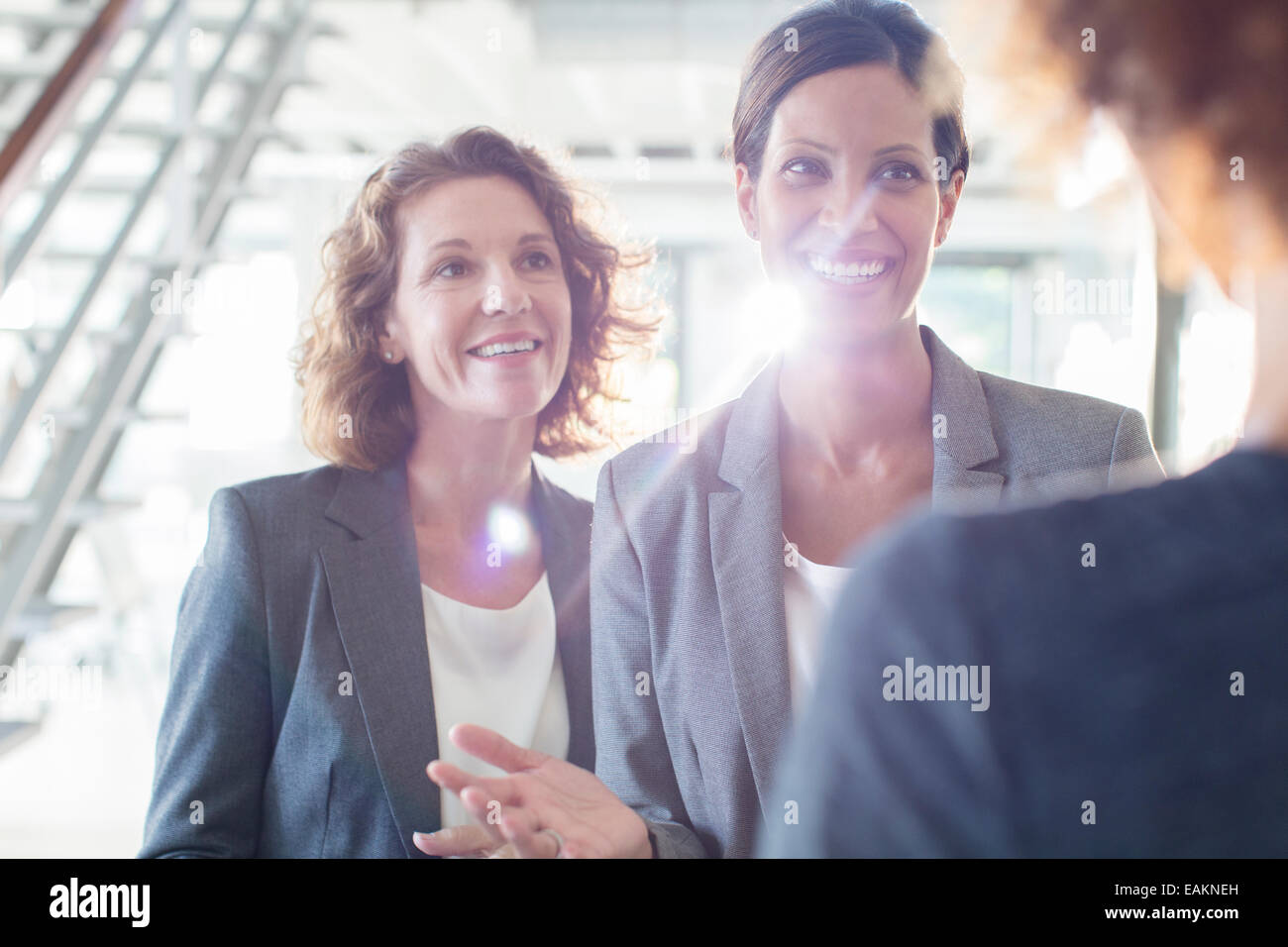Three smiling businesswomen talking in office corridor Stock Photo - Alamy